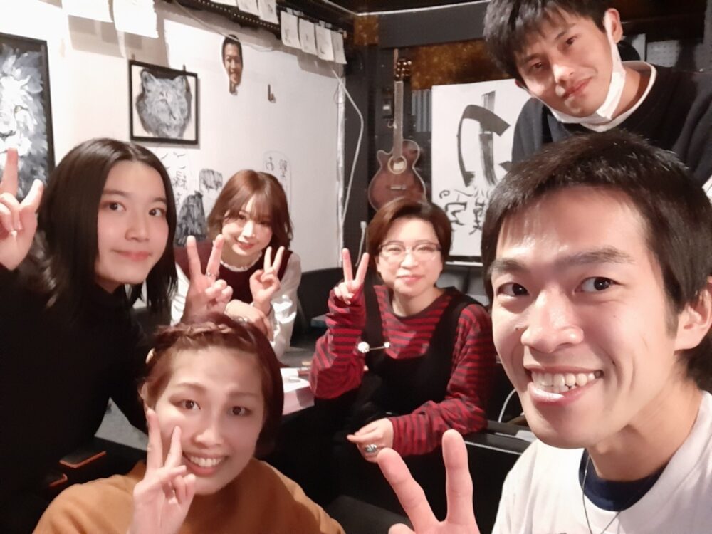 おしゃべりバーの店内で笑顔でピースサインをする人たち